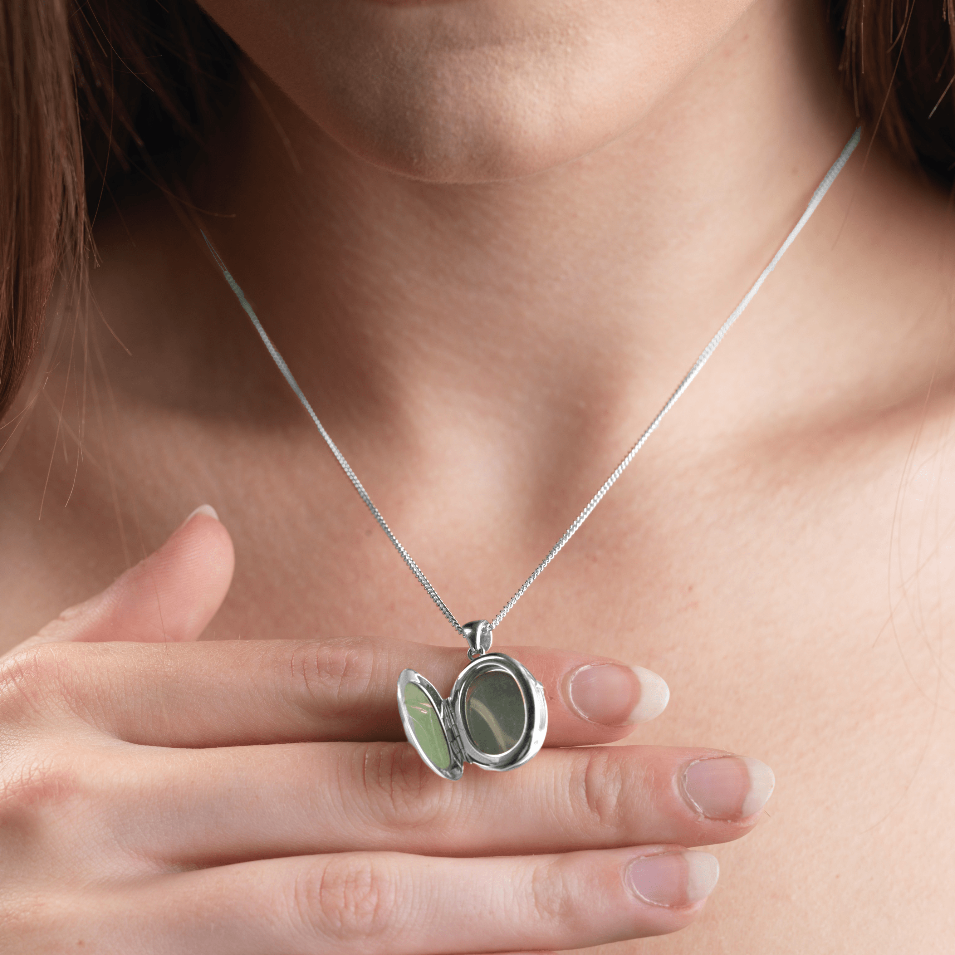 Model holding open a 9 ct white gold 4-photo oval locket on a 9 ct white gold curb chain
