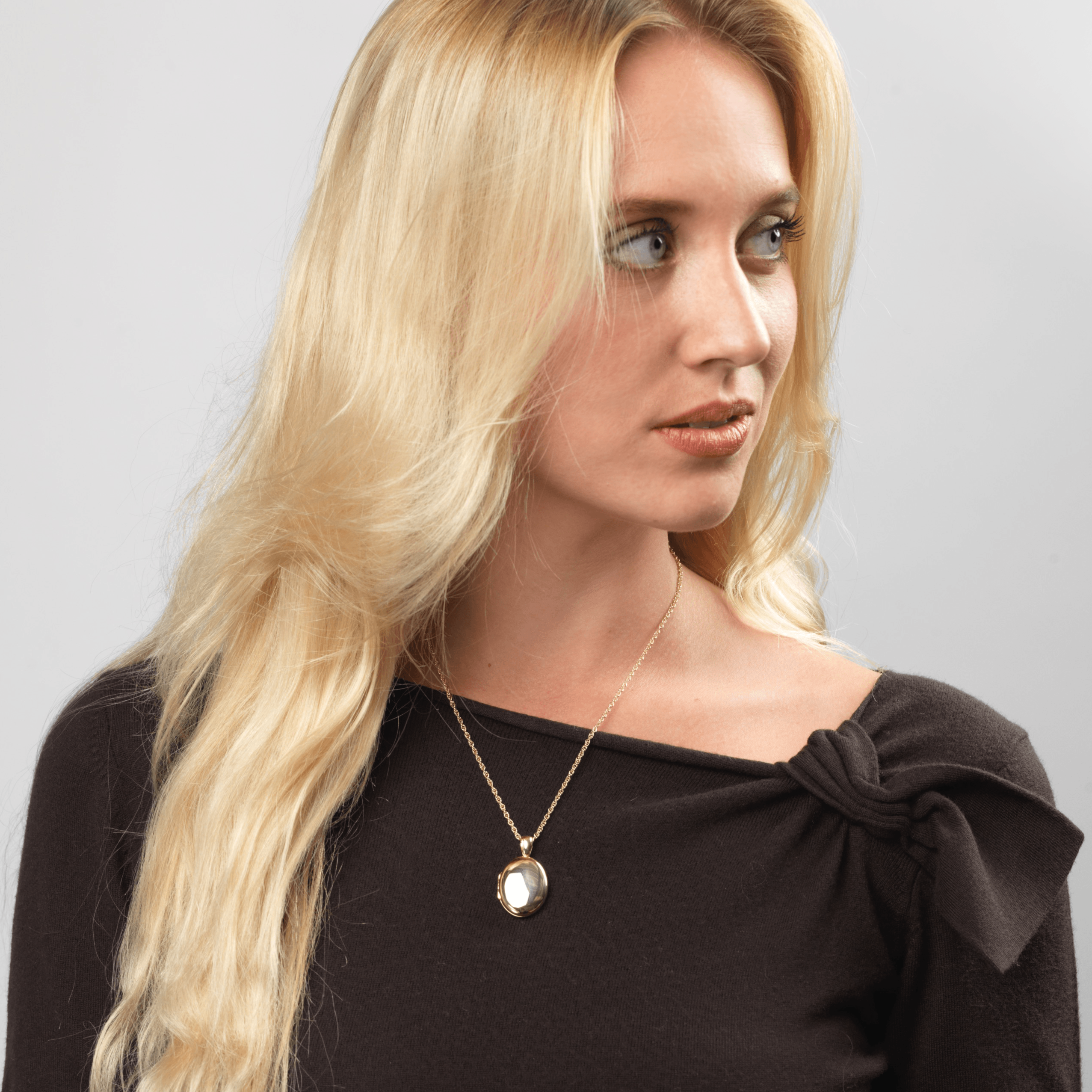 Model wearing an 18 ct gold oval locket on an 18 ct gold franco chain