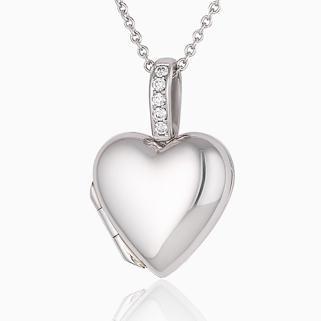 A platinum heart shaped locket, the bail set with diamonds, on a platinum chain.