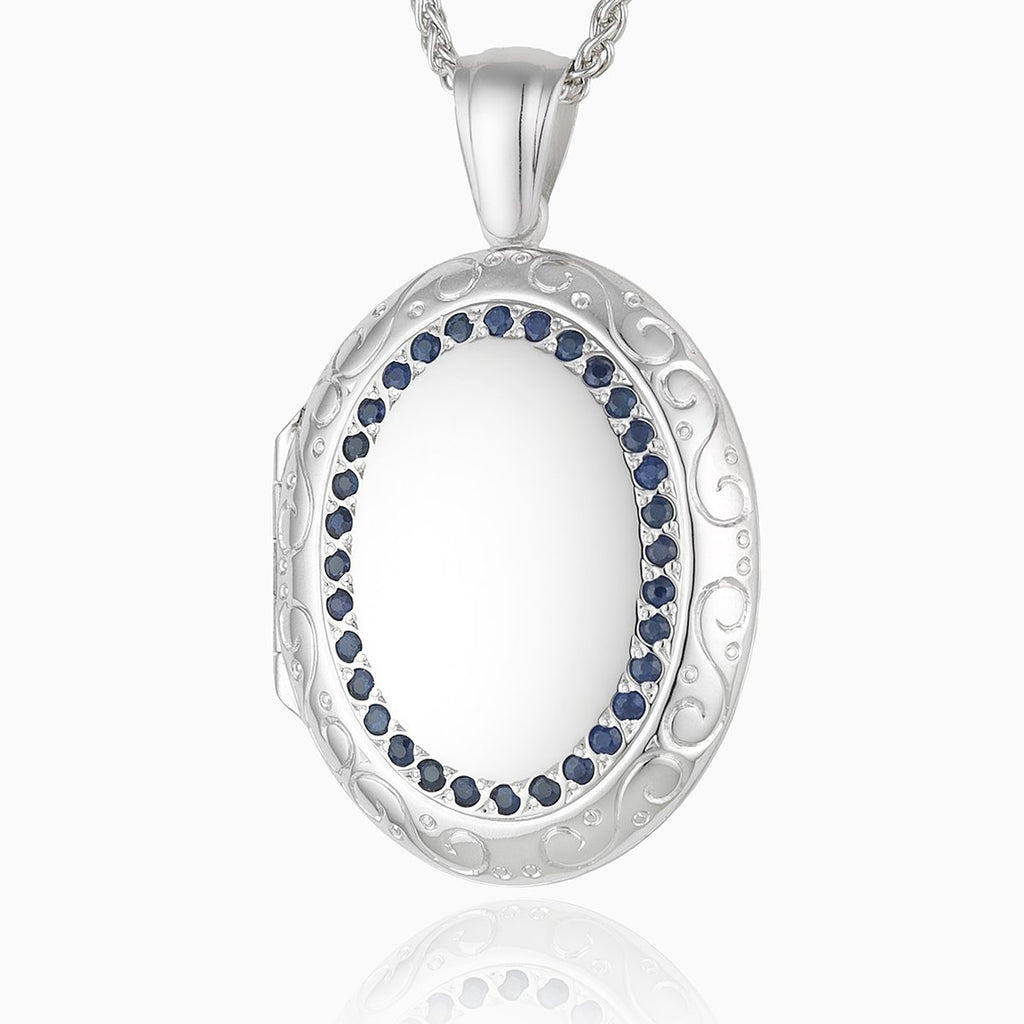 18 ct white gold large oval 4-photo locket set with blue sapphires and an engraved border, on an 18 ct white gold spiga chain