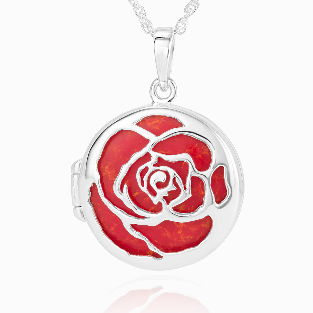 round sterling silver locket pierced out with a filigree rose design on the front, on an orange coral plaque