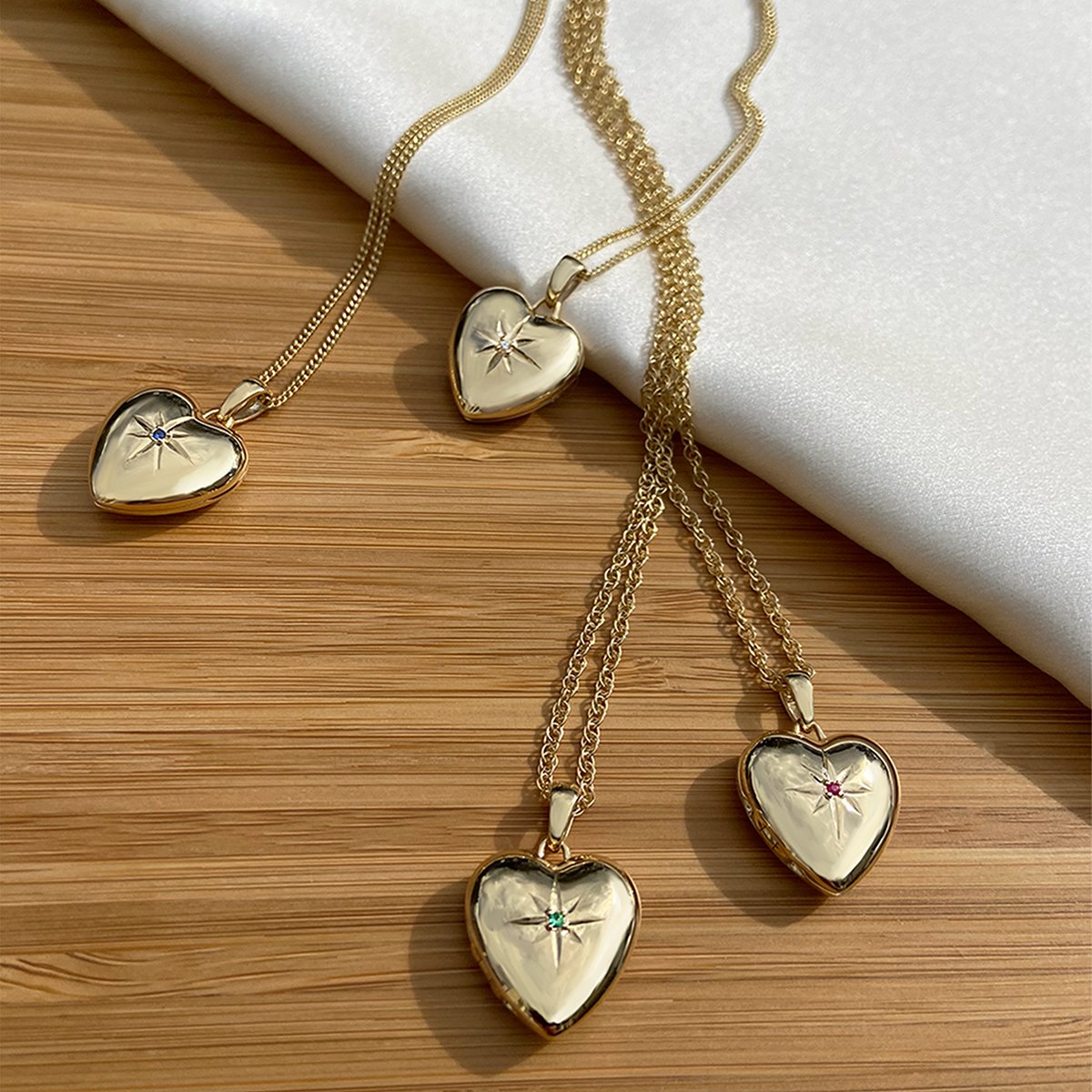 4 gold heart lockets , set with either a diamond, emerald, ruby or sapphire