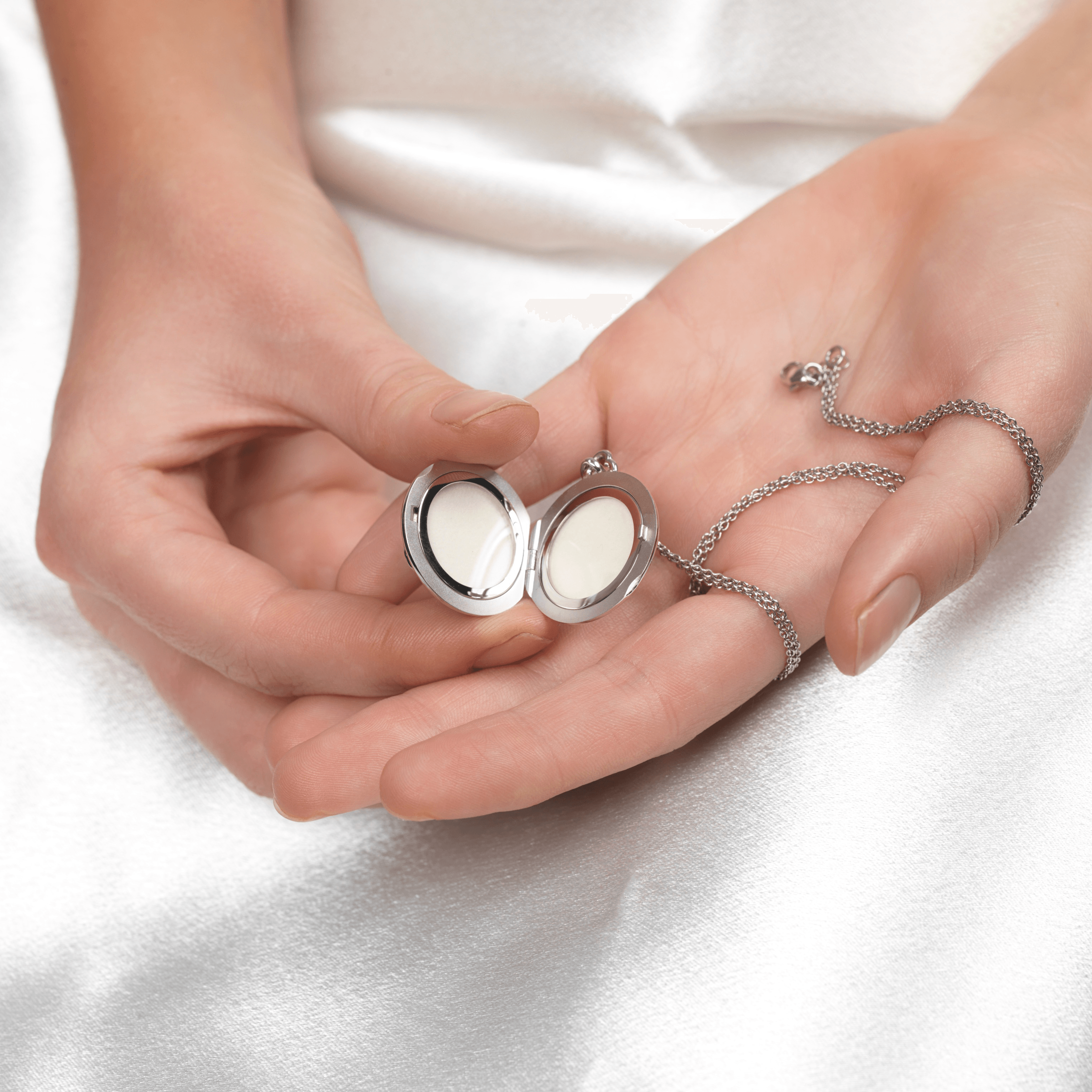Model holding open an 18 ct white gold round locket on an 18 ct white gold chain