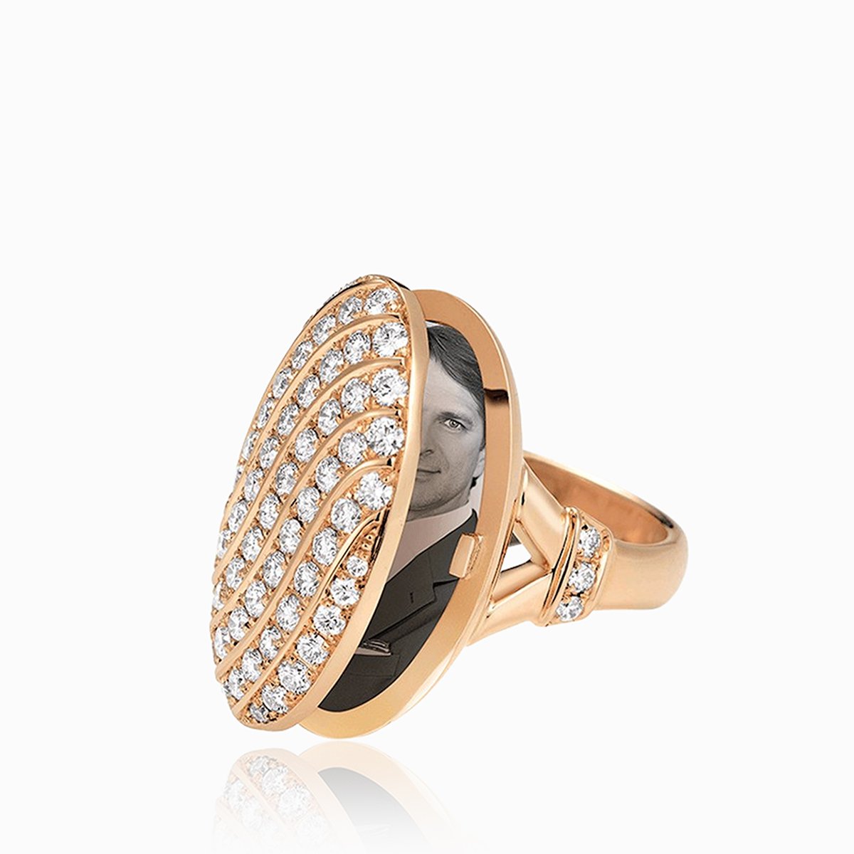 Open view of an 18 ct rose gold oval locket ring pave set with diamonds in a swirling design. The shank is also set with diamonds.