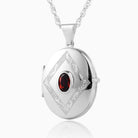 Sterling silver oval locket set with a red oval garnet in the middle and a rhombus shaped engraving, on a sterling silver rope chain.