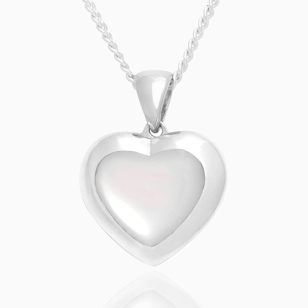 Front shot of a petite heart-shaped sterling silver locket set with white mother of pearl on a sterling silver curb chain.